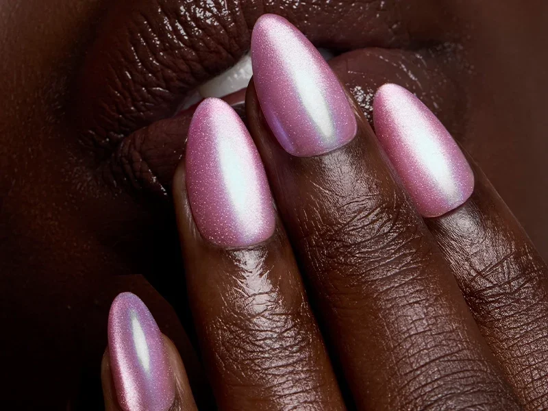 Close-up of a hand with pearly pink chrome almond press-on nails